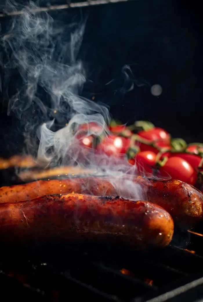 Salzburger Grillwurst Metzgerei Schultes am Grill mit Cocktailtomaten